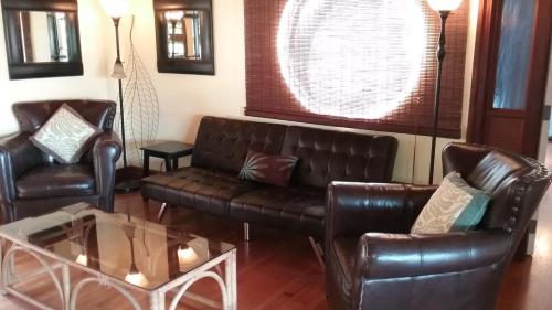 a living room with two leather couches and a table at Hawaii Tropical Volcano mansion + Sauna in Hilo