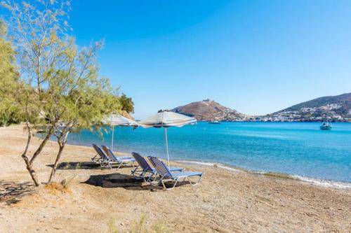 two lounge chairs and an umbrella on a beach at Atlazia Suites in Alinda