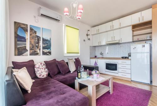 a living room with a purple couch and a table at Apartments Inspiration in Budva