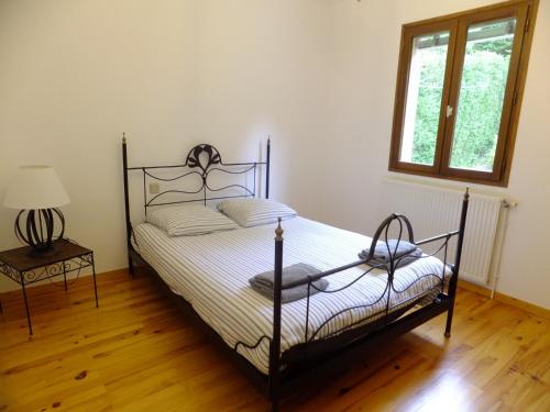 1 dormitorio con cama, lámpara y ventana en Le Clos Gentiane en Saint-Étienne