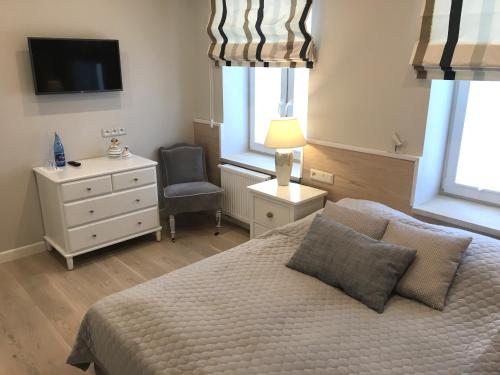 a bedroom with a bed and a chair and a television at Willa Błękit Hotel by Dorota Szelągowska in Mielno
