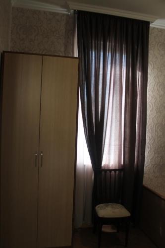 a bedroom with a curtain and a chair and a cabinet at Green Guest House in Kutaisi