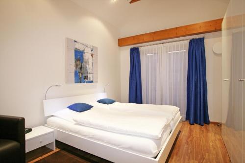 ガルミッシュ・パルテンキルヒェンにあるFerienwohnung Am Kurpark -Wohnung 3,150qm- mit Liftの白いベッド(青い枕付)が備わるベッドルームです。