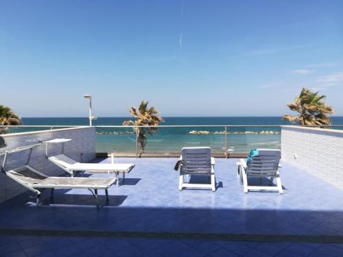 eine Terrasse mit Stühlen, Tischen und Meerblick in der Unterkunft Residence Acqua di Mare in Termoli