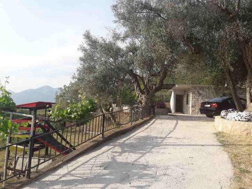 a driveway with a fence and trees and a car at Apartman Nikocevic in Dobra Voda