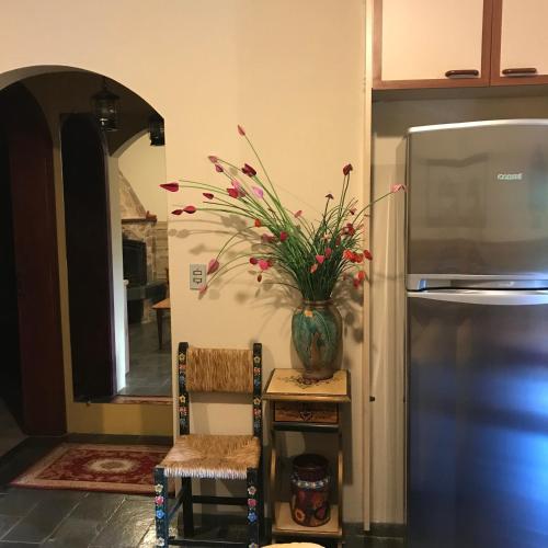 a vase of flowers sitting on a table next to a refrigerator at Hospedagem Casadalee chalé com piscina privativa aquecida e Apartamento sem piscina in Monte Verde