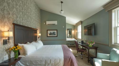 a bedroom with a bed and a desk and a chair at The Groton Inn in Groton