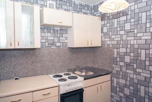 a kitchen with white cabinets and a stove at Апартаменты на Курской in Tyumen