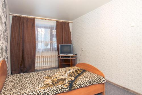 a bedroom with a leopard print bed and a television at Апартаменты на Курской in Tyumen