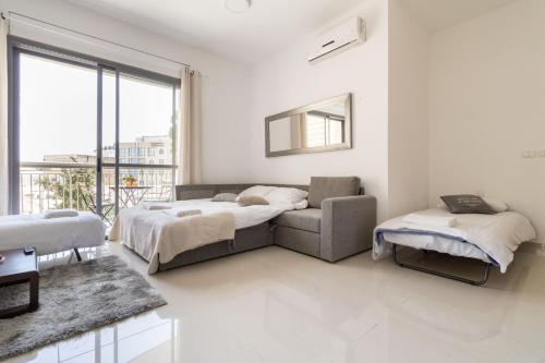 a bedroom with two beds and a couch and a window at Yafo 35 -Isrentals in Jerusalem