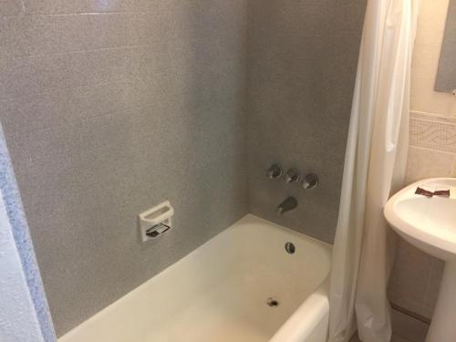 y baño con bañera, aseo y lavamanos. en Frontier Motel en Anaheim