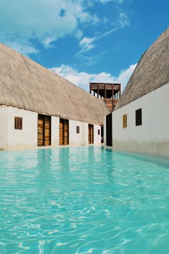 a pool of water in front of two buildings at Hotel Boutique Punta Caliza - Adults Oriented in Holbox Island
