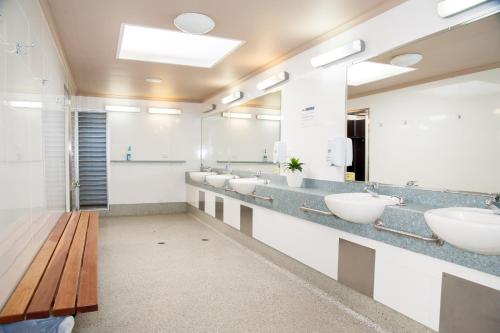 a bathroom with four sinks and a wooden bench at NRMA Batemans Bay Resort in Batemans Bay