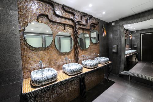 a bathroom with three sinks and two mirrors at The Pinewood Hotel in Slough