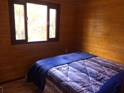 a bedroom with a bed in a room with a window at Casa de Campo Vale Rio dos Bugres in Urubici