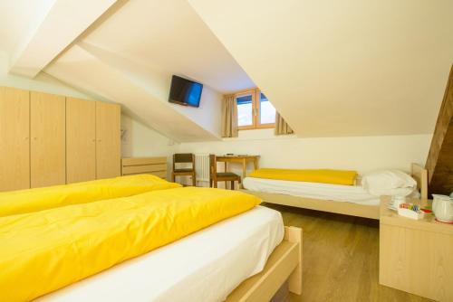 a bedroom with two beds with yellow sheets at Hotel Regina Delle Dolomiti in Panchia