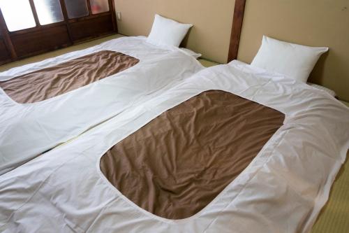 a bed with a brown blanket on top of it at Guest House Hitsujian in Kyoto