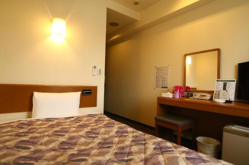 a hotel room with a bed and a desk and a mirror at Hotel New Budget Sapporo in Sapporo
