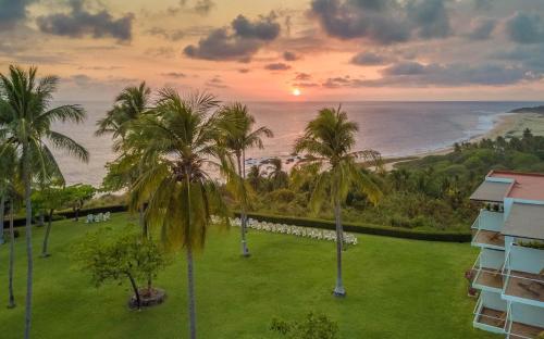 a view of the ocean from a resort with palm trees at Posada Real Puerto Escondido in Puerto Escondido