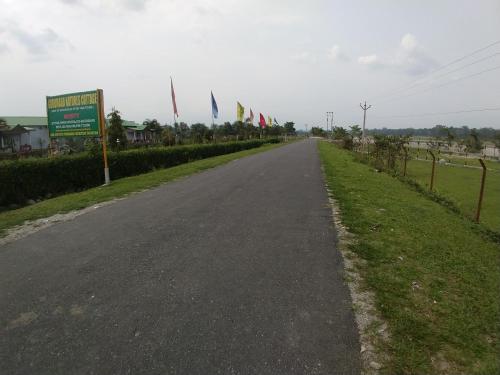 an empty road with flags on the side of it at Gorumara Nature's Cottage (A Unit Of M/S Ecological & Tours) in Jalpāiguri