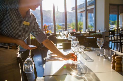 a man is setting a table in a restaurant at Peppers Blue on Blue in Nelly Bay