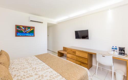 a bedroom with a bed and a desk and a tv at Posada Real Puerto Escondido in Puerto Escondido