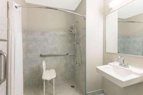 a white bathroom with a sink and a shower at Microtel Inn by Wyndham Henrietta in Henrietta