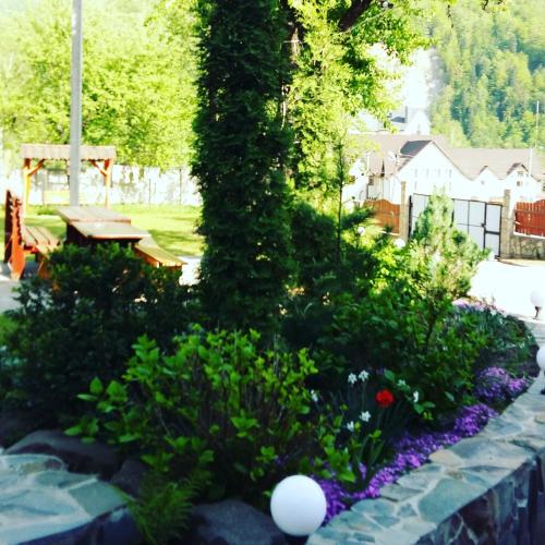 a garden with flowers and a tree with a bench at Karpatska Mria in Yaremche