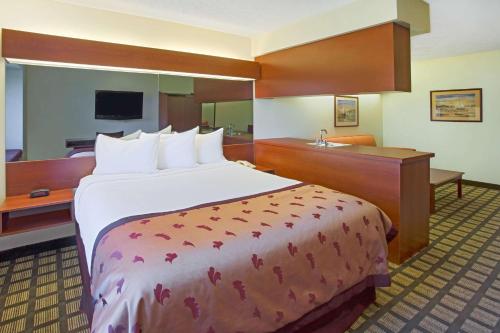 a hotel room with a large bed and a desk at Microtel Inn & Suites by Wyndham Holland in Holland