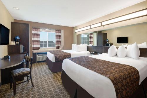 Habitación de hotel con 2 camas y escritorio en Microtel Inn & Suites by Wyndham Williston en Williston