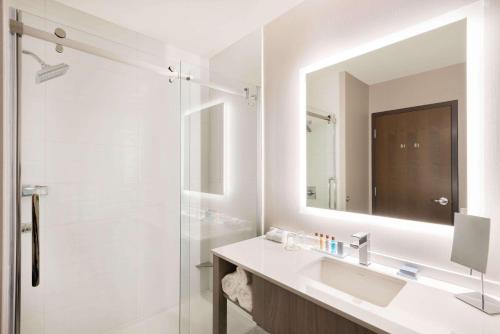 a bathroom with a sink and a shower with a mirror at Wingate by Wyndham Dieppe Moncton in Moncton