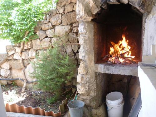 a stone fireplace with a fire in it at Crni in Gdinj