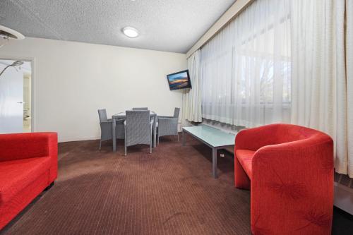 a dining room with red chairs and a table at Belconnen Way Hotel & Serviced Apartments in Canberra