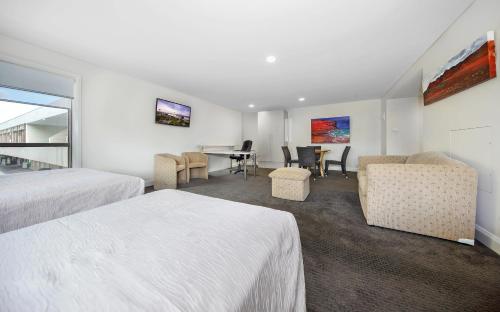 a hotel room with two beds and a table and chairs at Belconnen Way Hotel & Serviced Apartments in Canberra