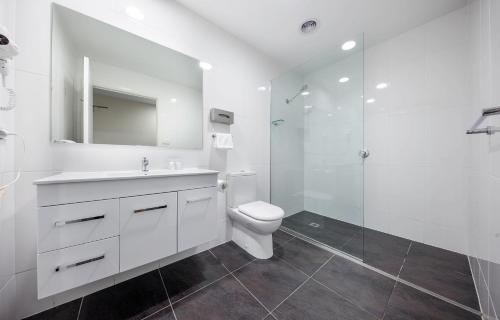 a white bathroom with a toilet and a shower at Belconnen Way Hotel & Serviced Apartments in Canberra