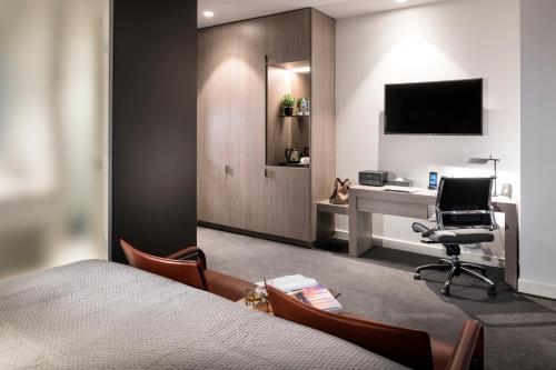 a bedroom with a bed and a desk with a computer at The Melbourne Hotel in Perth