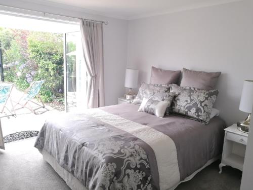 a white bedroom with a large bed and a sliding glass door at Terra Nostra in Mapua