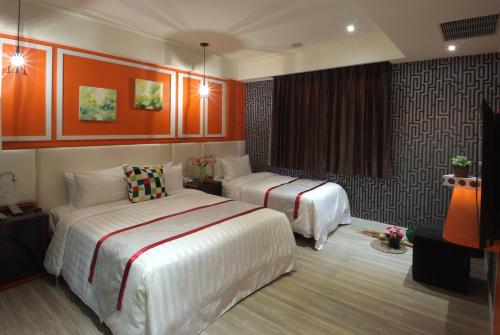 a hotel room with two beds and orange walls at Cai-Lai Motel in Yangmei