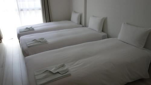 two white beds in a room with a window at Bay Hotel Urayasu-ekimae in Urayasu