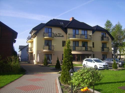 a building with a car parked in front of it at Willa Ludwik SPA & Wellness in Dębki