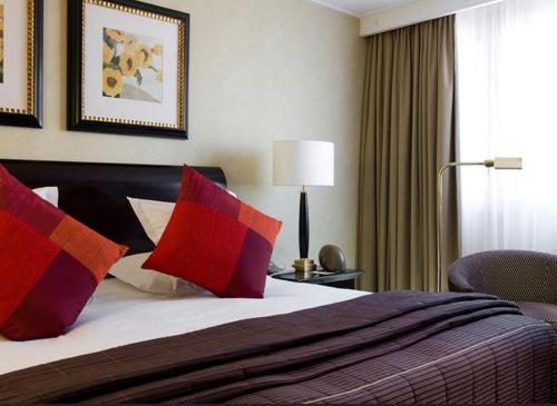 a hotel room with a bed with red and purple pillows at Warwick Champs-Elysées Paris in Paris