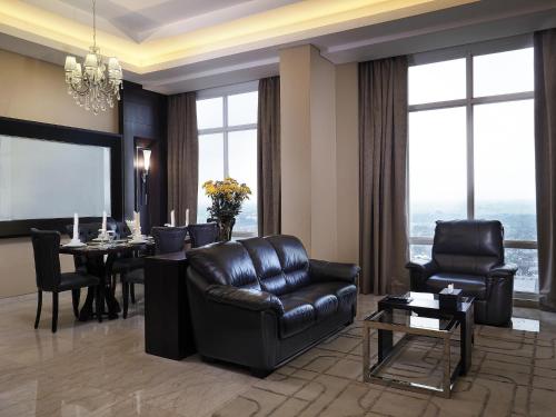 a living room with leather furniture and a table at Grand Mercure Solo Baru in Solo