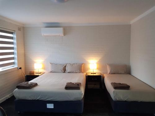 duas camas num pequeno quarto com duas lâmpadas em City Waters em Perth