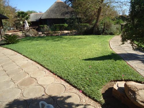 a grassy yard with a pathway and a house at Phokoje Bush Lodge in Selebi-Pikwe