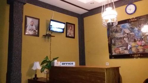 a living room with a tv and a wall with pictures at Murdhasari in Ubud