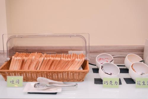 ein Korb mit Brot und Geschirr auf dem Tisch in der Unterkunft Cai-Lai Motel in Yangmei