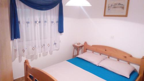 a bedroom with a bed and a window with blue curtains at Lubin in Sevid