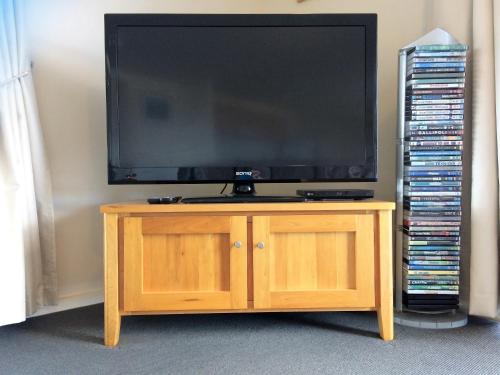 a television on a wooden stand with a dvds at Bayview Beach House Apartment No 2 in Kingscote