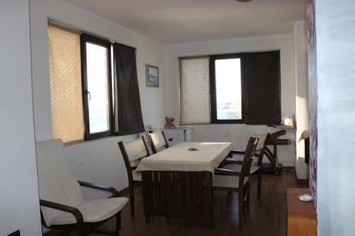 a dining room with a table and chairs and windows at Guest House Dara in Tsarevo