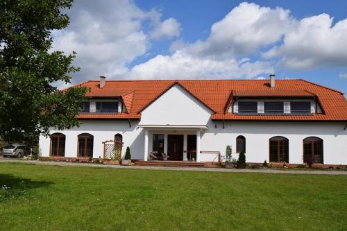 une maison blanche avec un toit orange dans l'établissement Lipowy Dwór, à Szczecinek